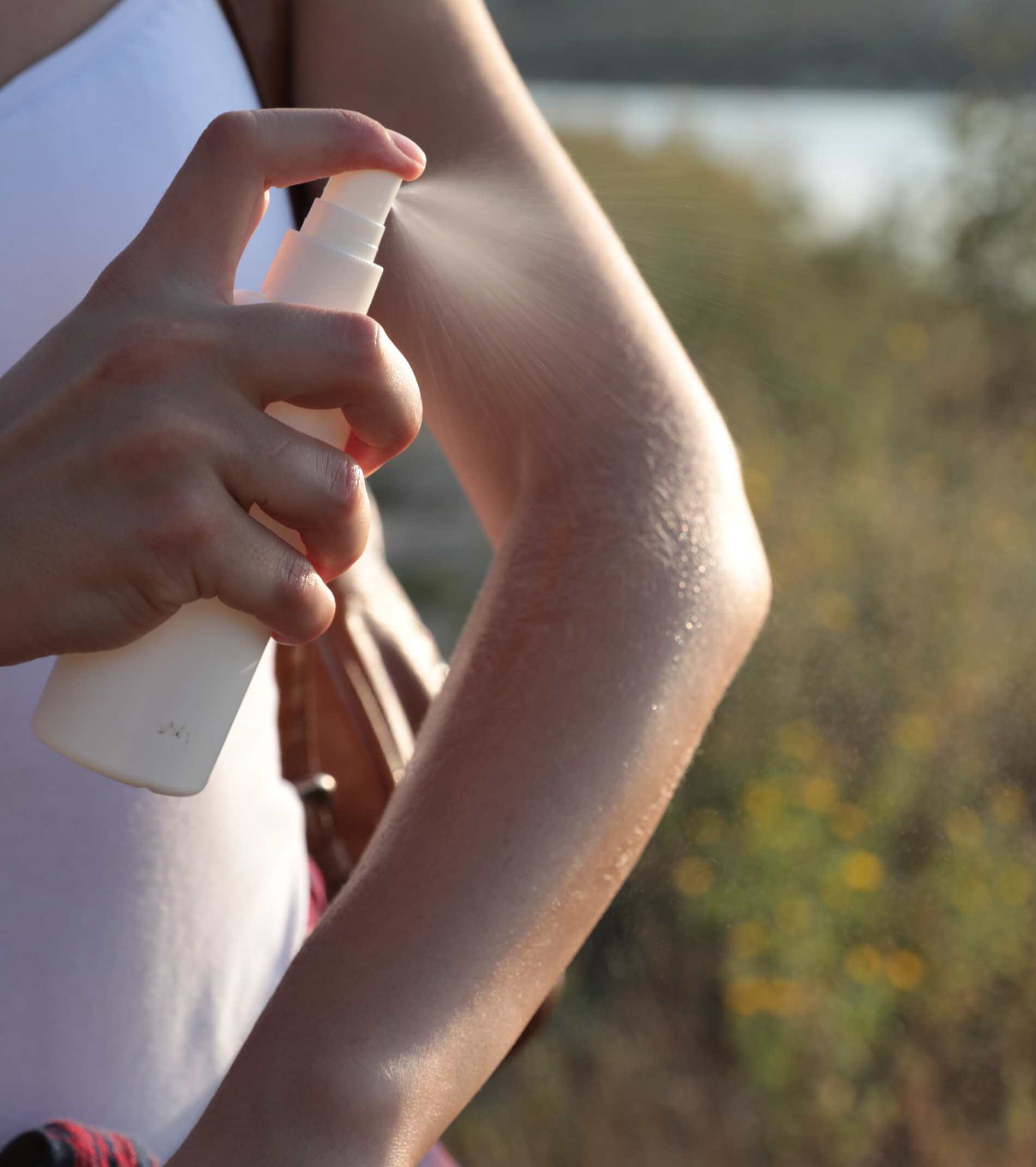 Woman applying insect repellent onto arm outdoors, closeup. Space for text
